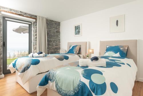 twee eenpersoonsbedden in een slaapkamer met een raam bij BHF Residences Ying Yang in Calheta