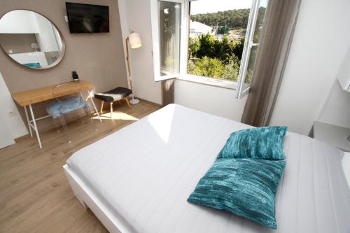 a white bed with a blue pillow on it in a room at Apartments Besker in Makarska