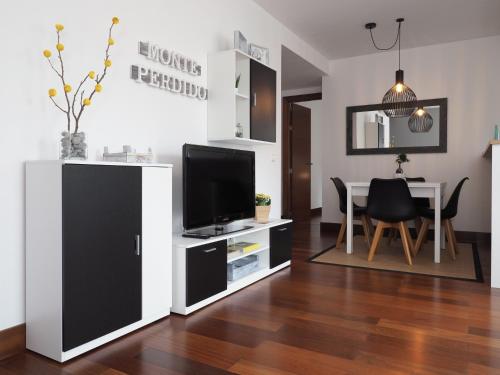 ein Wohnzimmer mit einem TV und einem Esstisch in der Unterkunft Apartamento Monte Perdido in Boltaña