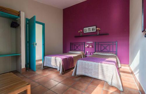 two beds in a room with purple walls at Hotel Patio de las Cruces in Seville