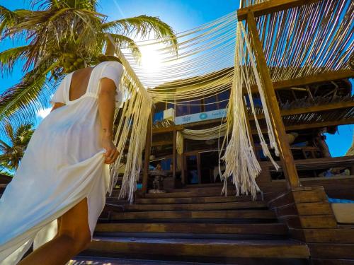 a woman in a white dress walking up steps to a building at Amansala Resort in Tulum