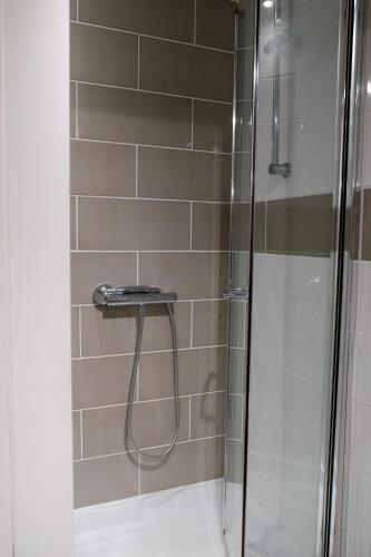 a shower with a glass door next to a tile wall at York House Durham in Durham