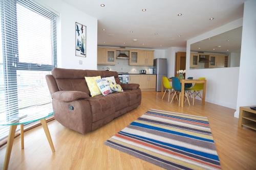 a living room with a couch and a kitchen at Horizons Apartments Newquay in Newquay