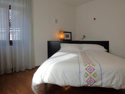 a bedroom with a large white bed with a lamp at Affittacamere Ca' Fattorini in Baceno