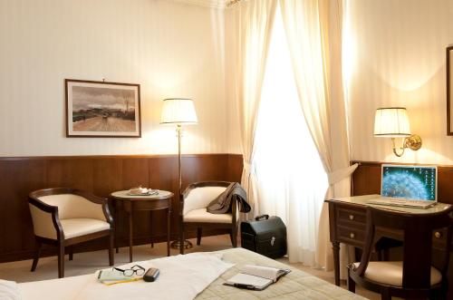 a hotel room with a bed and a desk and chairs at Grand Hotel Bastiani in Grosseto