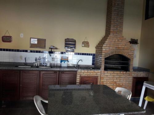 uma cozinha com um forno de tijolo e uma mesa com cadeiras em Condomínio Pousada Amarela 100 metros da Praia em Iguaba Grande