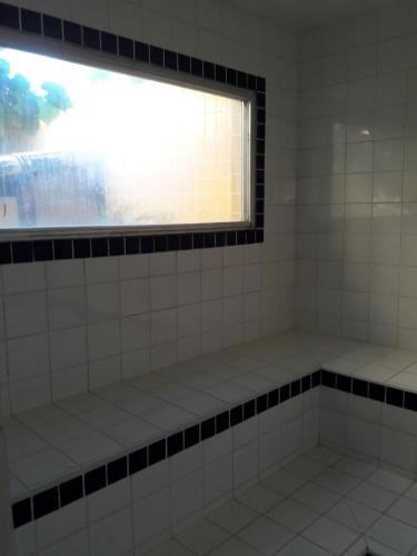 a bathroom with a window and white tiles at Condomínio Pousada Amarela 100 metros da Praia in Iguaba Grande
