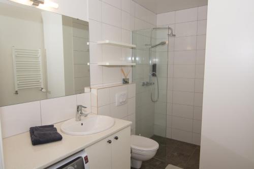a white bathroom with a sink and a toilet at Acco Town Square Apartments in Akureyri