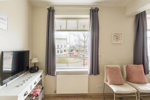 a living room with a tv and a window at Acco Town Square Apartments in Akureyri