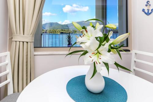 a white vase with white flowers on a table at Apartments Maestral in Tivat