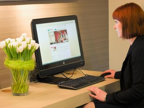 a woman sitting at a desk with a computer at Ramada by Wyndham Baden Hotel du Parc in Baden