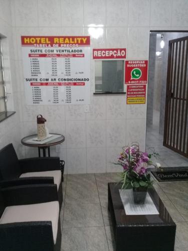 a waiting room with a couch and a table and signs at Motel Reality in Sao Paulo