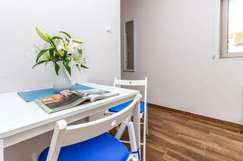 a table and chairs with a vase of flowers on it at Apartments Maestral in Tivat