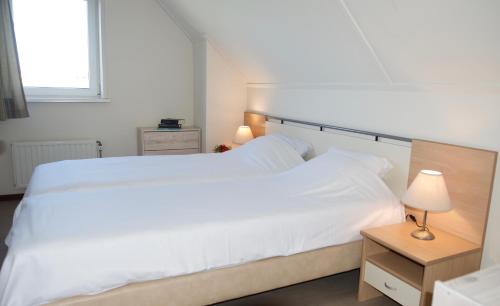 Un dormitorio con una gran cama blanca y una ventana. en Antibes 252 - Kustpark Village Scaldia, en Hoofdplaat