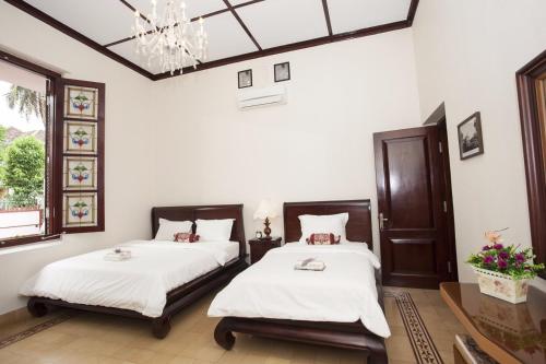 2 Betten in einem Zimmer mit weißen Wänden und einem Kronleuchter in der Unterkunft Huis Van Gustafine Floor 1 in Malang
