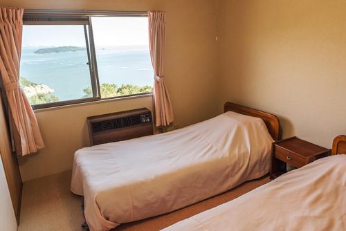um quarto com 2 camas e uma grande janela em ペンションみかんの郷 em Bizen