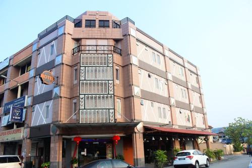 un grand bâtiment en briques avec des voitures garées devant lui dans l'établissement Rock & Roll Hotel Klang, à Klang