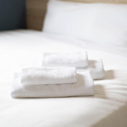 two white towels sitting on top of a bed at Super Hotel Okinawa Nago in Nago