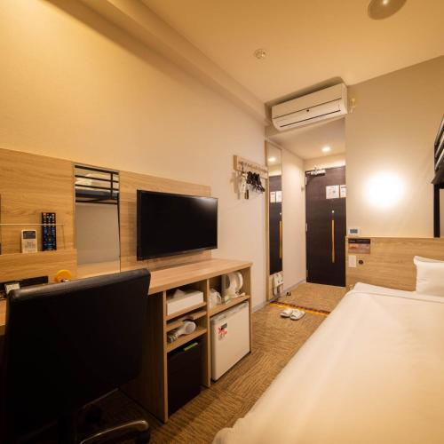 a hotel room with a bed and a flat screen tv at Super Hotel Okinawa Nago in Nago