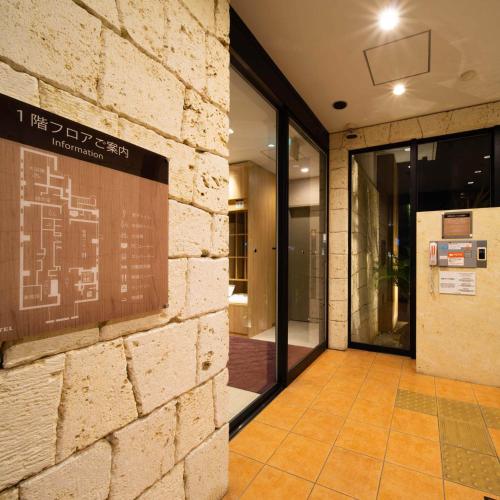 an entrance to a building with a sign on the wall at Super Hotel Okinawa Nago in Nago