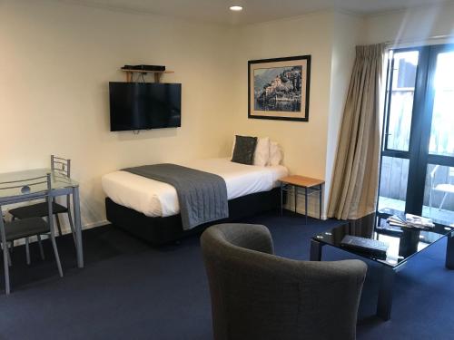 a hotel room with a bed and a tv at Claremonte Motor Lodge in Hastings