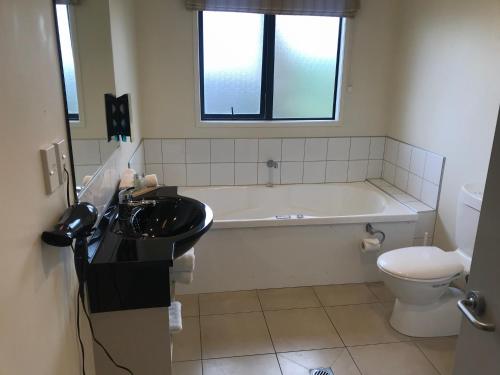a bathroom with a sink and a tub and a toilet at Claremonte Motor Lodge in Hastings