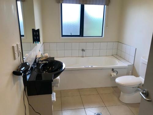 a bathroom with a sink and a tub and a toilet at Claremonte Motor Lodge in Hastings