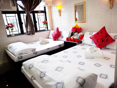 2 łóżka w pokoju z biało-czerwonymi poduszkami w obiekcie Melbourne Hostel Block E 10th floor w Hongkongu
