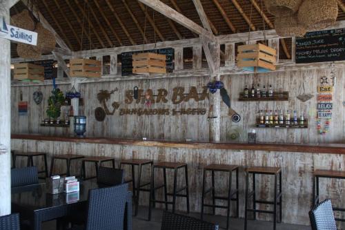 een restaurant met een bar met stoelen en flessen wijn bij Star Bar and Bungalows in Gili Air