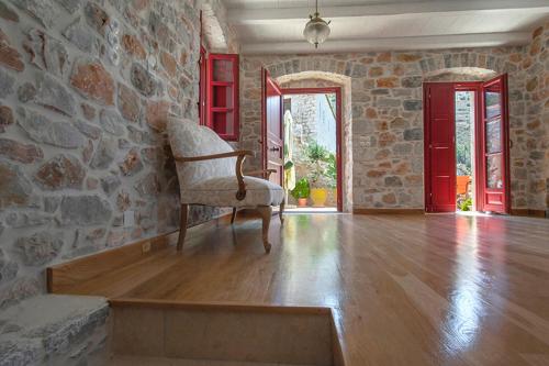 salon z kamienną ścianą i krzesłem w obiekcie Limeni Villa w mieście Limeni