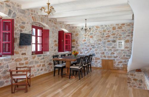 jadalnia z kamiennymi ścianami oraz drewnianym stołem i krzesłami w obiekcie Limeni Villa w mieście Limeni