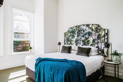 a white bedroom with a large bed with a large headboard at The Florance in Launceston