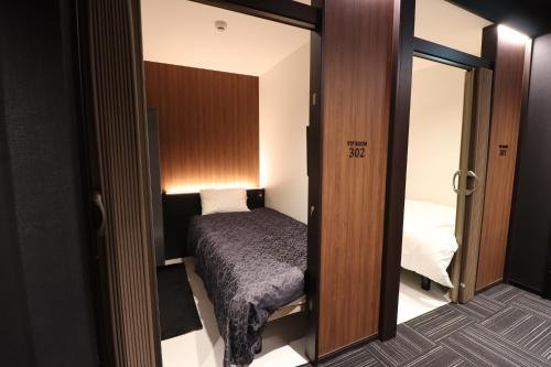 a small room with a bed and a mirror at LEO YU Capsule Hotel Nishifunabashi in Funabashi