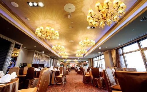 a dining room with tables and chairs and chandeliers at The Howard Prince Hotel Taichung in Taichung