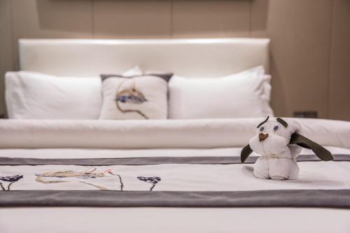 a stuffed animal sitting on top of a bed at Metropolo Jinjiang Xuzhou Railway Station Suning Plaza Chudu in Xuzhou