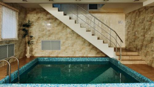 a swimming pool with a staircase and a swimming pool at Goldman Empire in Astana