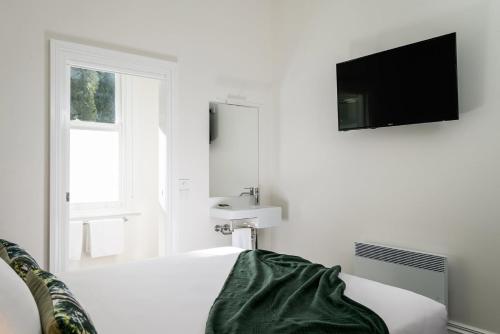 a white room with a bed and a tv on the wall at The Florance in Launceston
