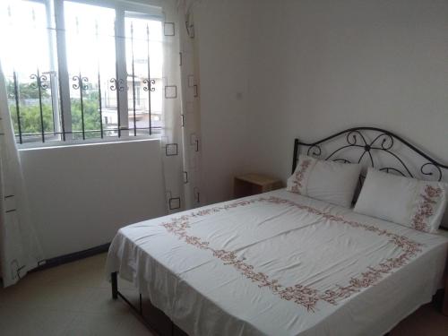 a bedroom with a bed with white sheets and a window at Villa FRANCOISE in Pereybere