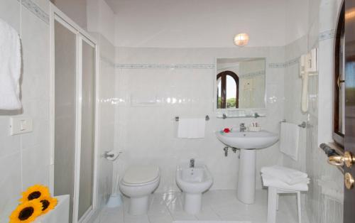 a white bathroom with a toilet and a sink at Residence Cala Di Mola in Porto Azzurro