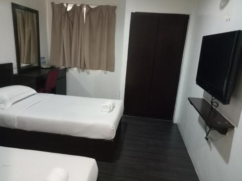a small room with a bed and a television at Hotel Sri Bernam in Sabak Bernam