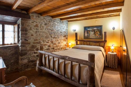 1 dormitorio con cama y pared de piedra en Casa de Aldea Vache, en Naraval