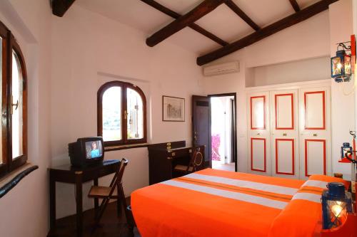 ポルト・アッズッロにあるHotel Cala di Molaのベッドルーム(オレンジ色のベッド1台、テレビ付)