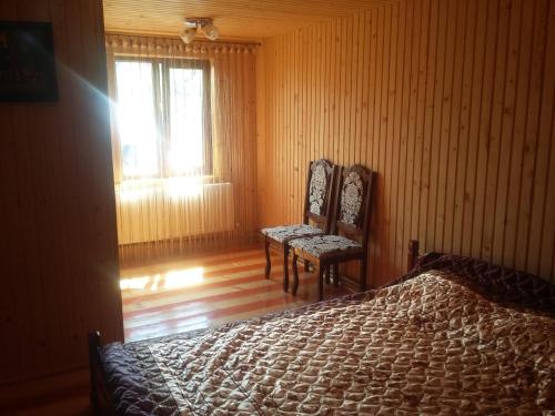 a bedroom with two chairs and a bed and a window at Zatushok pid goroyu in Verkhovyna