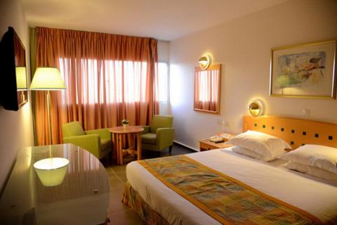a hotel room with two beds and two lamps at Aquamarine Hotel in Eilat