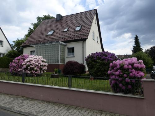 a white house with purple flowers in front of a fence at Ferienwohnung Baier in Erbach