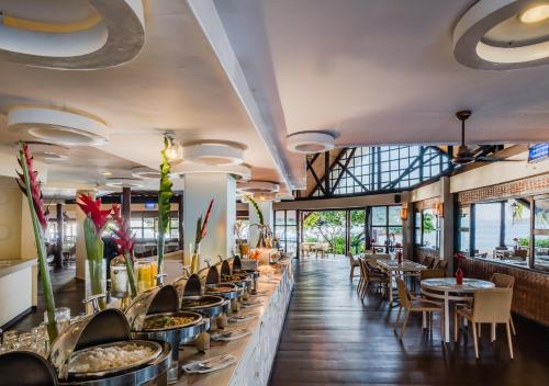 コロンにあるDiscovery Coron formerly Club Paradise Palawanのテーブルと椅子と窓のあるレストラン