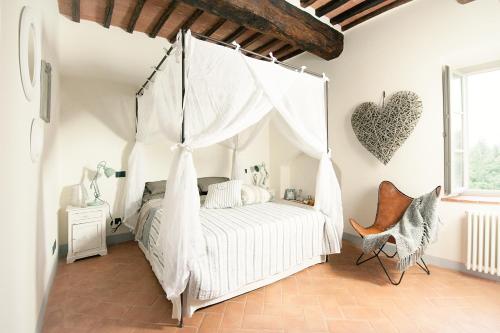 a white bedroom with a bed with a swing at la Senesina in Monteriggioni