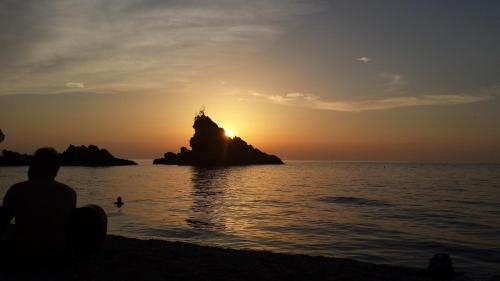 a person sitting on the beach watching the sunset at B&B Centro Storico 900 in Palmi