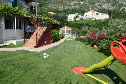 a dog laying on the grass next to a house at Apartments Tabain in Mlini