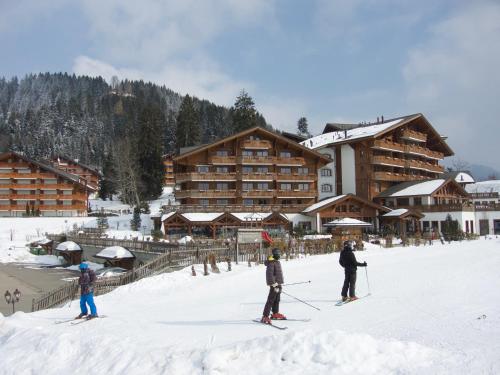 three people on skis in the snow in front of a lodge at Résidence RoyAlp - Appartement 22A in Villars-sur-Ollon
